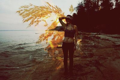 Silhouette of woman standing on beach at sunset