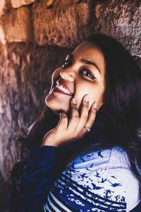 Close-up of portrait of woman smiling by stone wall