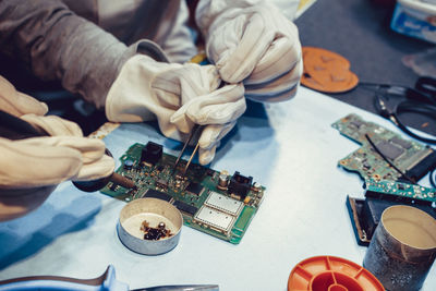 Cropped image of technicians repairing circuit board on table indoors