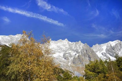 Low angle view of snowcapped mountains against blue sky