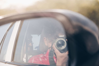 Portrait of man photographing through car