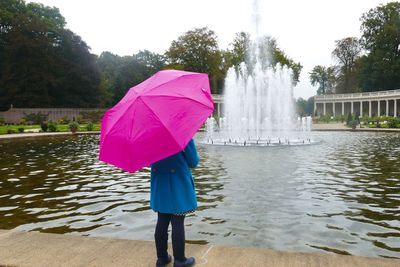 Rear view of man on wet umbrella against sky