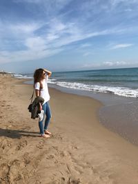 Full length of woman standing at beach against sky