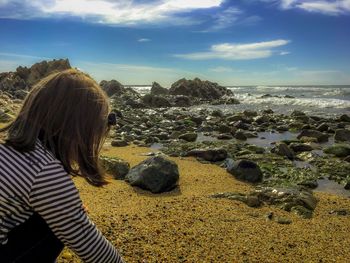 Rear view of woman standing by sea against sky