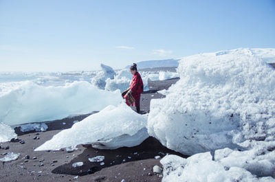 Woman on snow covered mountain against sky