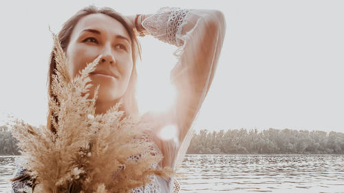 Portrait of beautiful young woman against sky