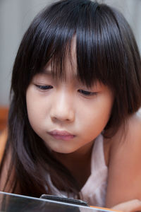 Close-up of girl using digital tablet while lying down on sofa at home