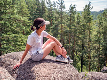 Girl is sitting alone on the rock. solo travel. leisure activity, hiking.