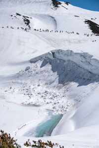 Scenic view of snow covered mountains against a lot of people 