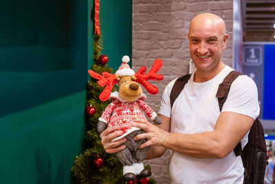 A cheery bald man holds a dear toys in his hand in the store