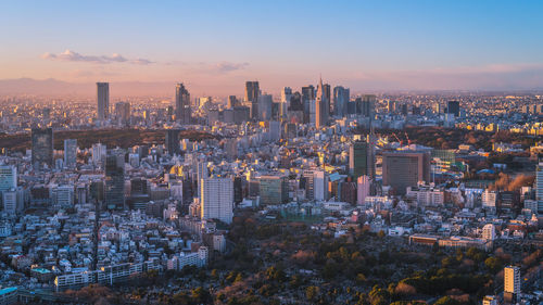 Aerial view of modern buildings in city against sky during sunset