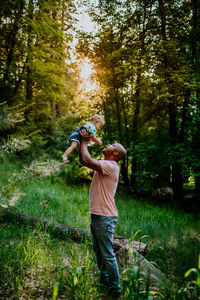 Vertical portrait of dad holding infant son up in the air
