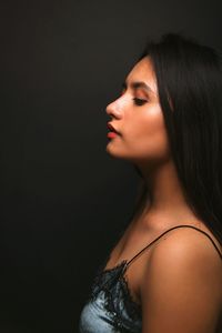 Profile view of beautiful woman standing against black background