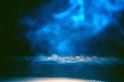 Defocused image of illuminated sea against sky at night