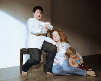 Full length of mother and grandmother sitting on chair at home