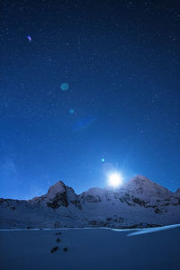 Scenic view of snowcapped mountains against sky at night