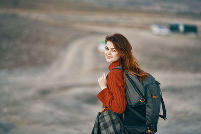 Young woman looking away while standing outdoors