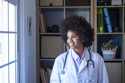 Smiling doctor looking through window at clinic