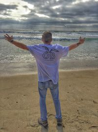 People on beach against cloudy sky