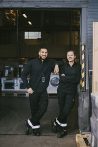 Male and female colleagues standing on doorway of distribution warehouse