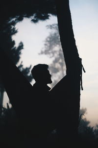 Low angle view of silhouette man against trees against sky