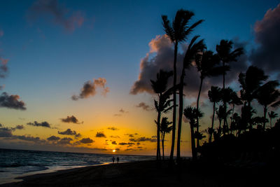 Silhouette palm trees on beach against sky during sunset