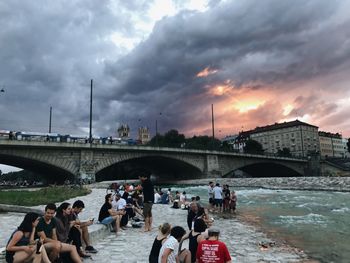 People on bridge over river against sky