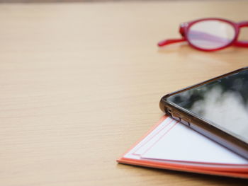 High angle view of smart phone with book on wooden table