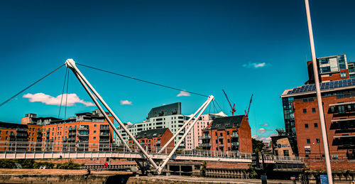 Low angle view of a bridge and buildings against blue sky in leeds, uk