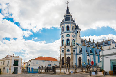 Low angle view of church against cloudy sky in city