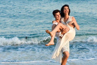 Young men carrying women at beach