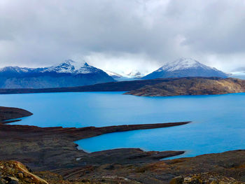 Scenic view of lake by snowcapped mountains against sky