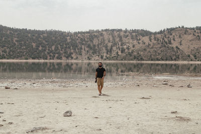 Full length of man standing on shore against sky