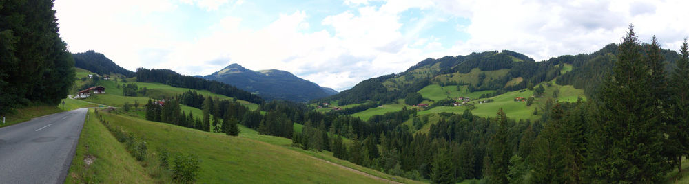 Panoramic view of green landscape and mountains against sky