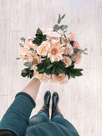 Low section of person standing by flower bouquet