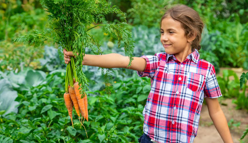 Cute girl holding carrots at farm