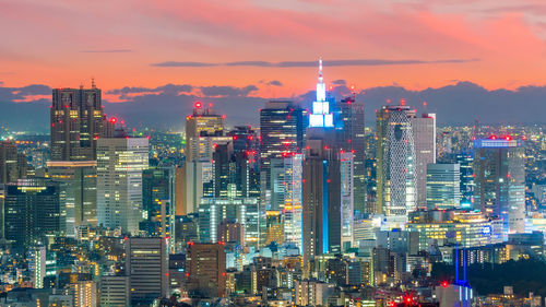 Illuminated buildings in city against sky during sunset