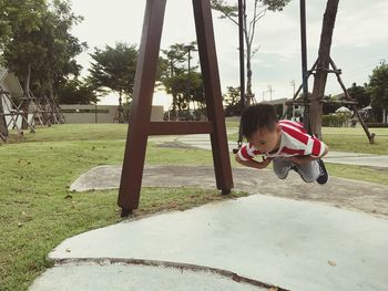 Boy playing on swing in park