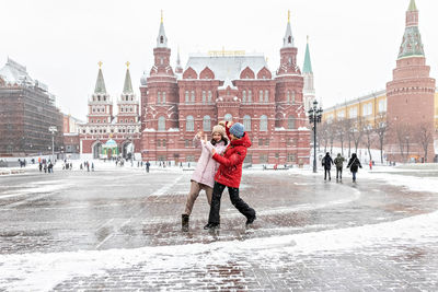 Full length of people on snow covered city during winter