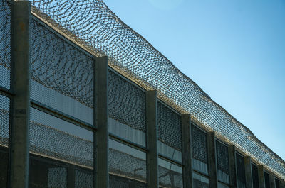 Low angle view of a security fence against sky