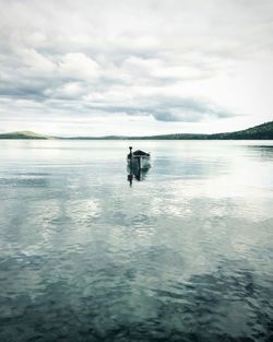 Boat on lake against cloudy sky