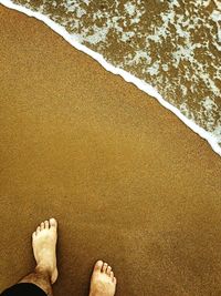 Low section of man relaxing on sand at beach