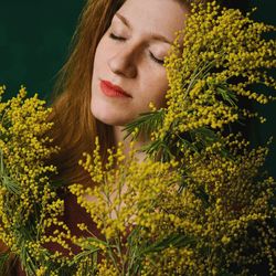Close-up of young woman with yellow flowers