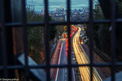 Light trails on street seen through metal grate