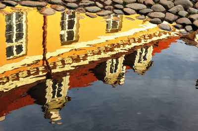 Reflection of building in puddle on cobbled street