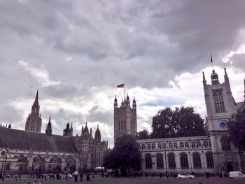 People at historical building against cloudy sky