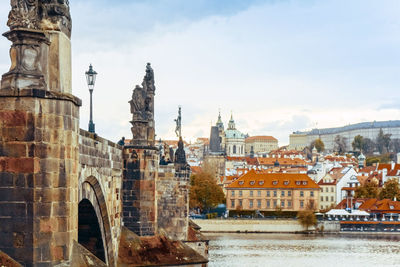 Charles bridge over vltava river against sky in city