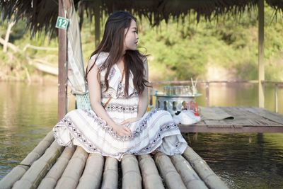 Woman sitting on wooden raft at lake