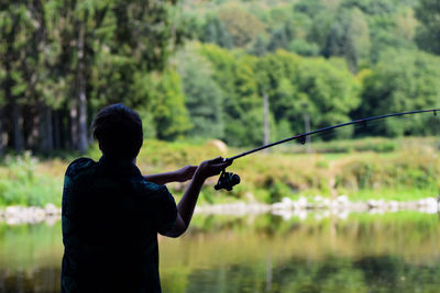Rear view of man fishing in lake