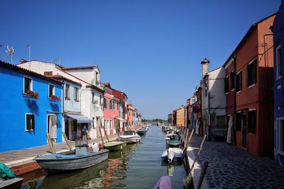 Boats moored in water against clear blue sky